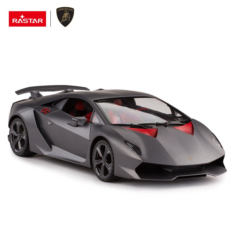 Rastar 1:14 Lamborghini Sesto Elemento RC car in matte grey photographed from the front 3/4 angle showing the large rear wing, open scissor-style door revealing the red interior with stereo and steering wheel details.