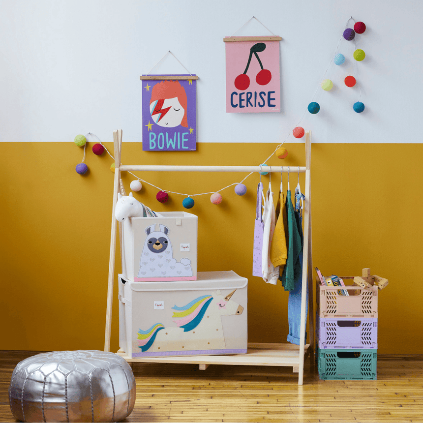 Children's room with a wooden wardrobe, colorful storage bins, and wall decorations.