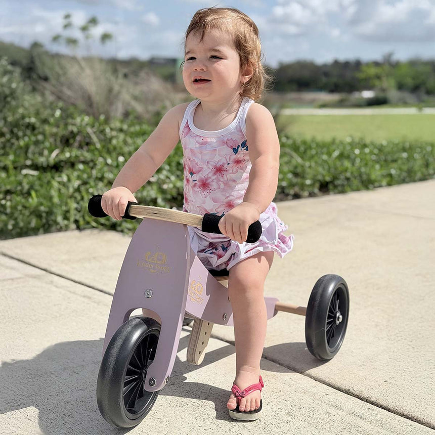 Toddler riding the Kinderfeets Tiny Tot Lavender trike outdoors