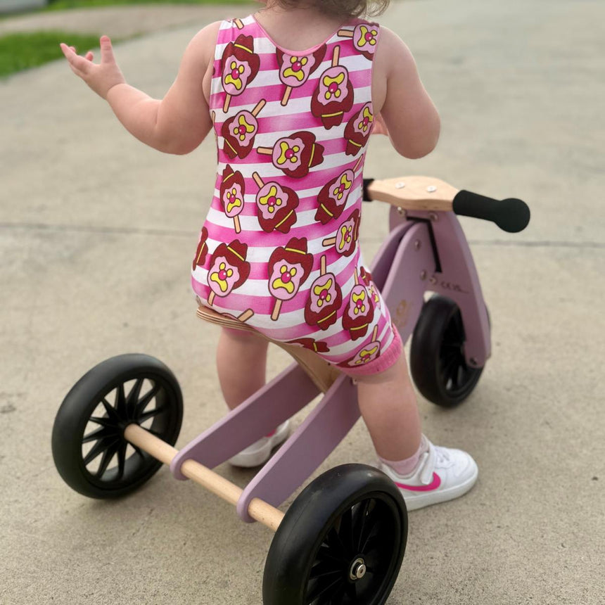 Toddler on the Kinderfeets Tiny Tot Lavender wooden trike on a footpath