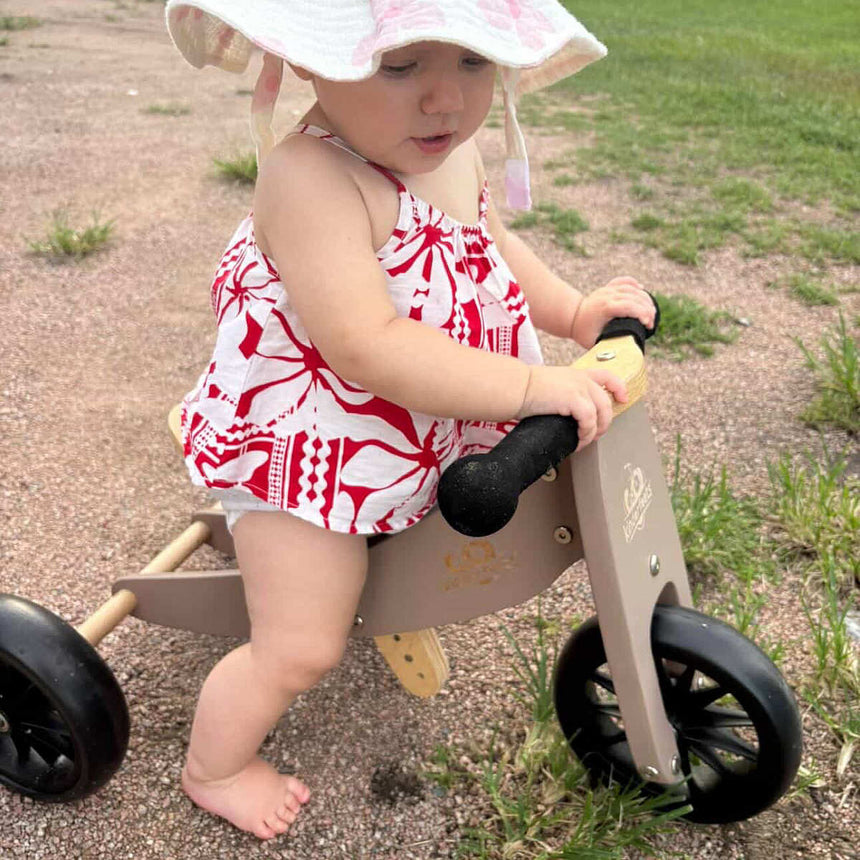 Toddler riding the Kinderfeets Tiny Tot Mocha balance bike outdoors