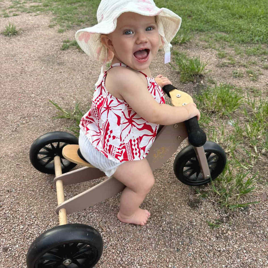 Happy toddler on the Kinderfeets Tiny Tot Mocha wooden bike