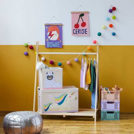 Children's room with a wooden wardrobe, colorful storage bins, and wall decorations.