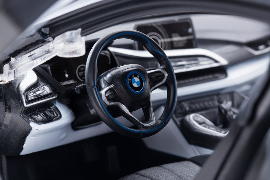 Close-up detail shot of the Rastar 1:14 BMW i8 RC car interior, showing the detailed BMW-branded steering wheel with blue trim, dashboard instruments, and centre console through the open butterfly door.