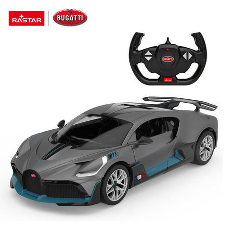Rastar 1:14 Bugatti Divo RC car in matte grey with teal/blue accents shown from a lower front 3/4 angle alongside the Bugatti steering wheel controller. The wide body kit, side air vents, and large fixed rear wing are clearly visible.