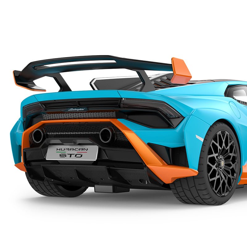 Closeup rear 3/4 detail shot of the Rastar 1:14 Lamborghini Huracan STO RC car in sky blue with orange accents. The image focuses on the large carbon-look rear wing, orange rear diffuser and bumper accents, dual exhaust pipes, and "Huracan STO" rear licence plate badge.