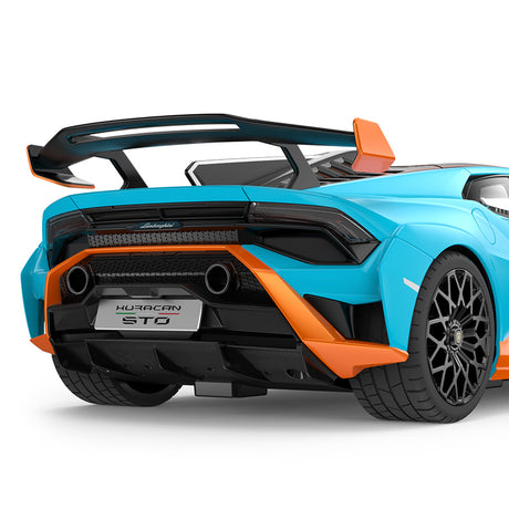 Closeup rear 3/4 detail shot of the Rastar 1:14 Lamborghini Huracan STO RC car in sky blue with orange accents. The image focuses on the large carbon-look rear wing, orange rear diffuser and bumper accents, dual exhaust pipes, and "Huracan STO" rear licence plate badge.