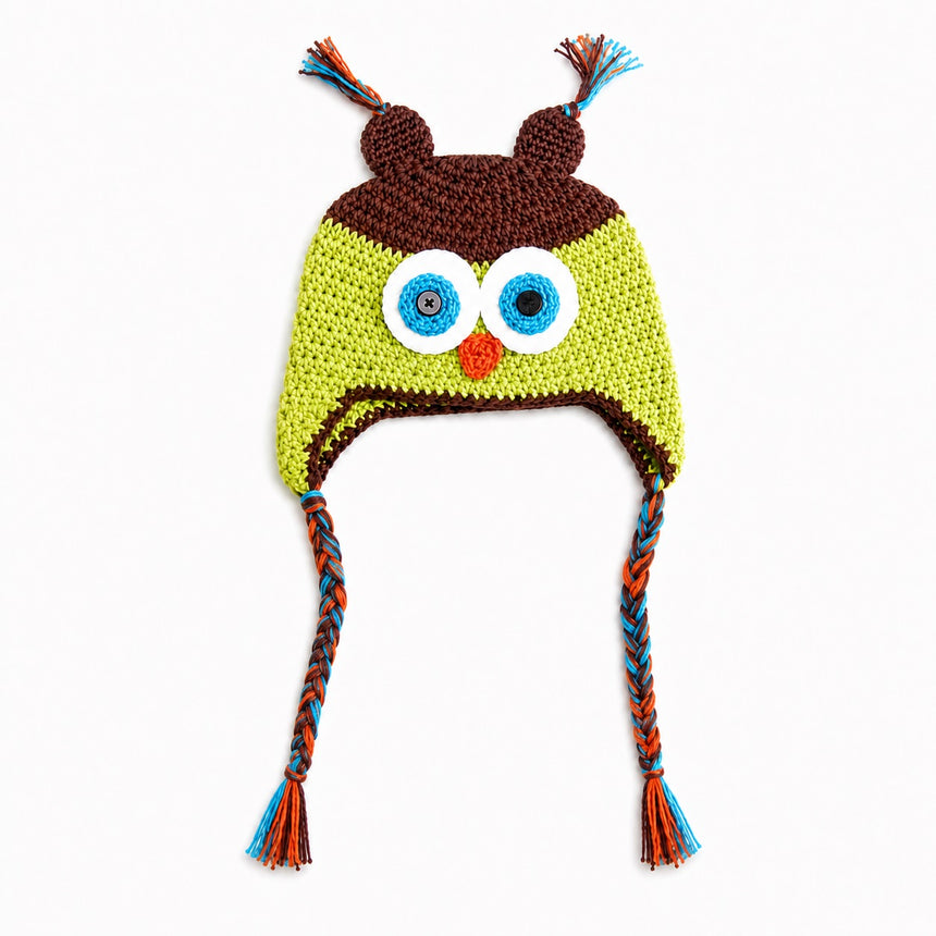 Crocheted owl hat with large embroidered eyes, a small orange beak, brown ear covers, and braided ear ties in blue, orange, and brown on a white background.