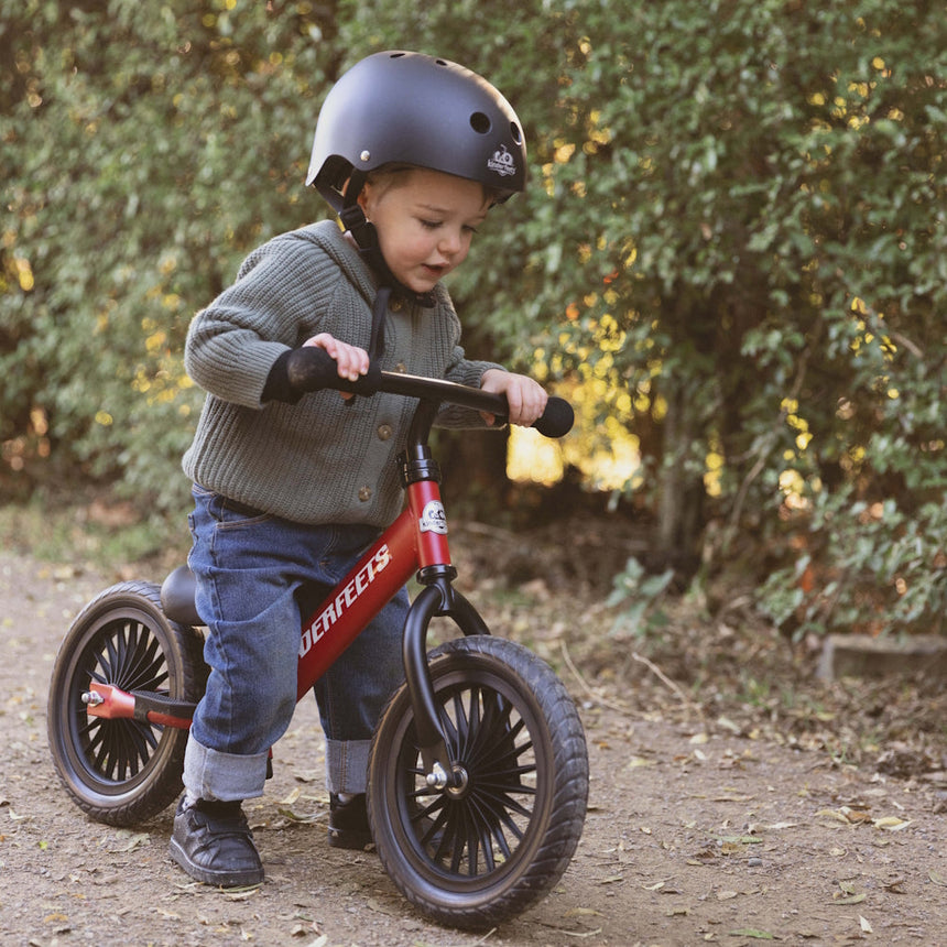 Toddler riding the Kinderfeets Trail Bike Cherry Red balance bike