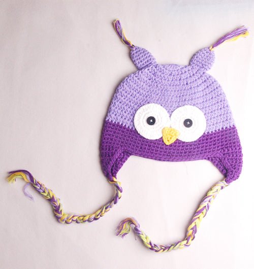 Flat lay detail of light purple and purple owl beanie with crochet eyes and braided ties