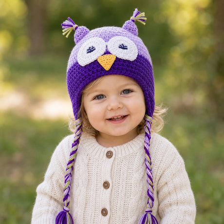 Toddler wearing light purple and purple crochet owl beanie hat in a park
