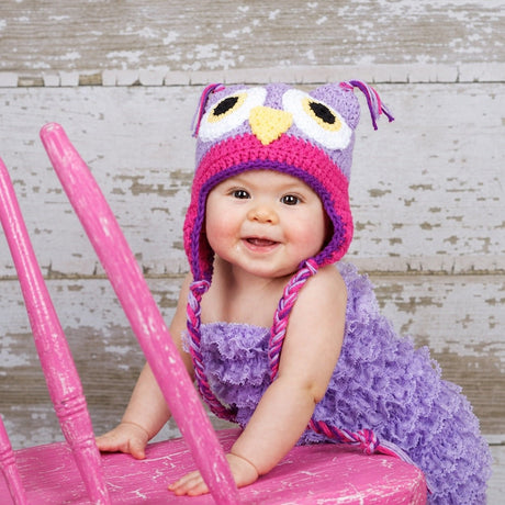 Baby wearing light purple and rose owl beanie with braided ties
