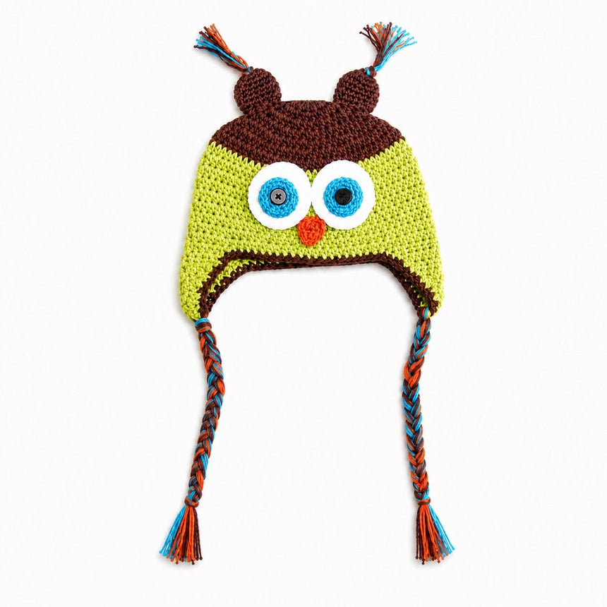 Crocheted owl hat with large embroidered eyes, a small orange beak, brown ear covers, and braided ear ties in blue, orange, and brown on a white background.