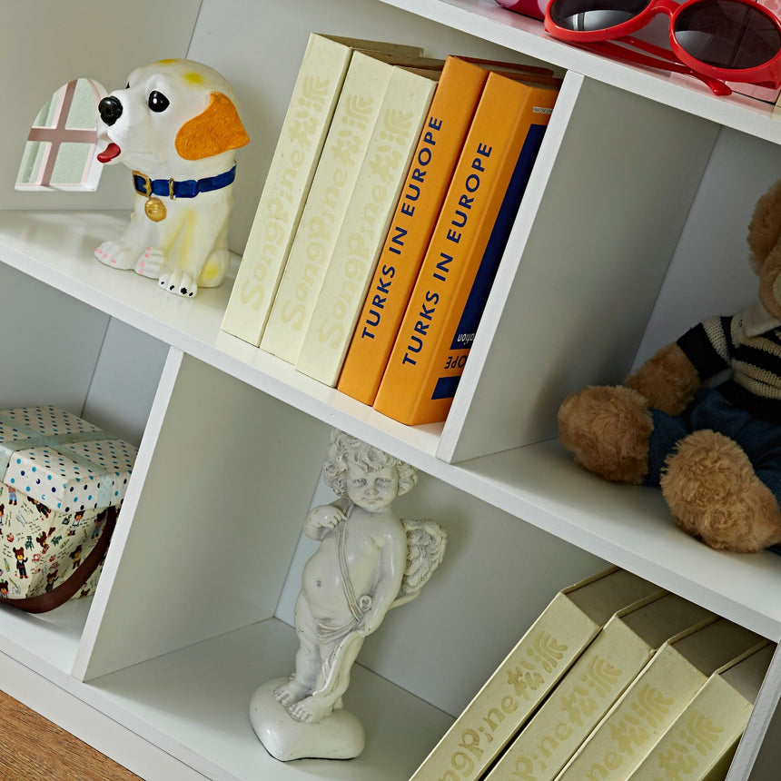 Storage shelf detail of the Veronica dollhouse bookcase with books and toys