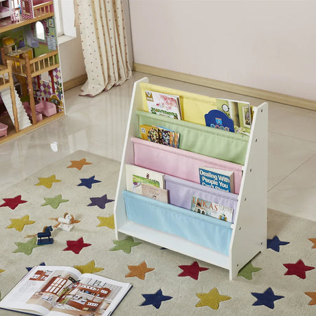 White wooden kids sling bookcase holding picture books, styled beside a dollhouse in a playroom