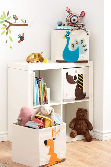 Children's toy storage cubes with animals on, filled with toys, on a white shelf.