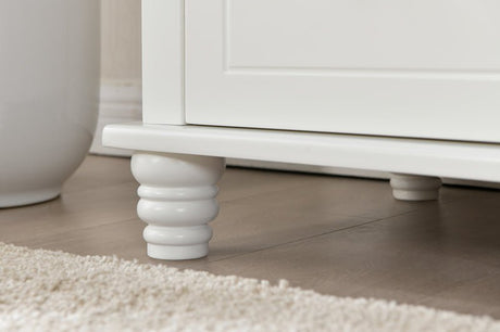 White wooden nursery furniture leg with rounded design on light wood floor and carpet
