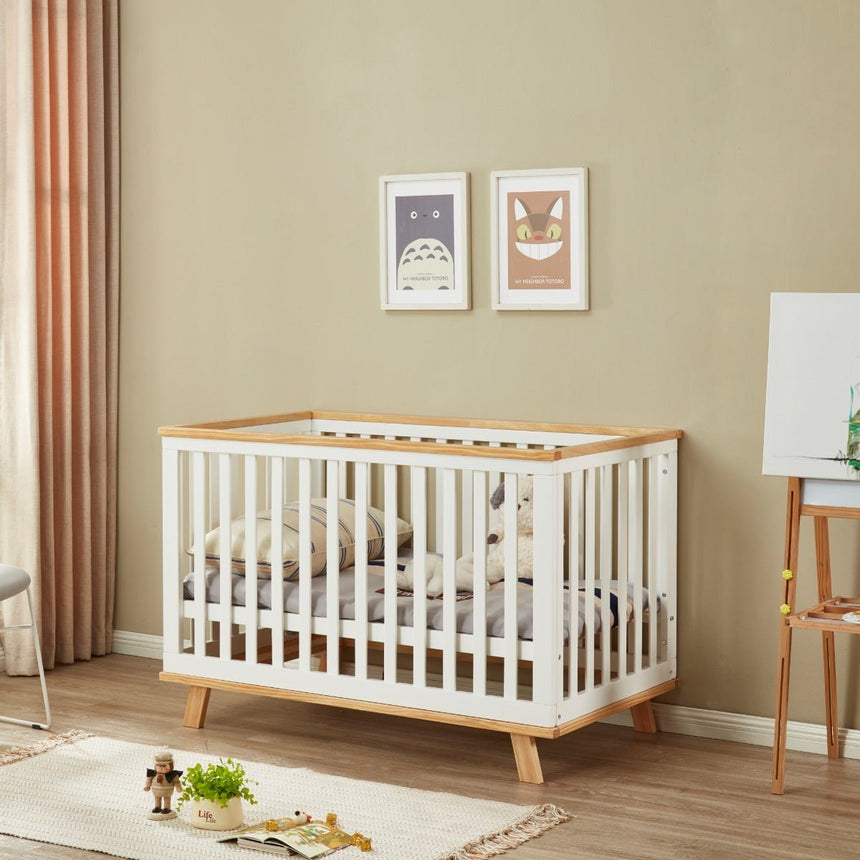 Modern white wooden baby cot in a cozy nursery with toys and wall art, kids furniture