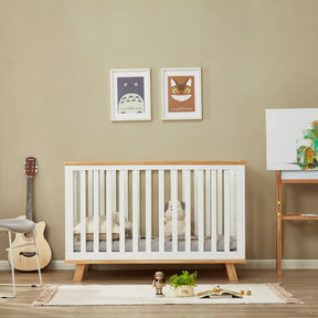 Modern nursery with white wooden cot, toys, wall art, guitar, and neutral decor.
