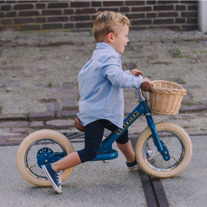 Child riding the Vintage Blue Trybike balance bike outdoors