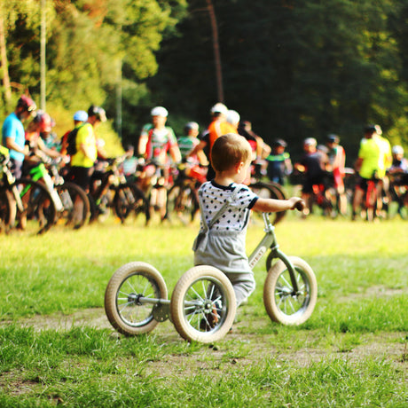 Child riding the Vintage Green Trybike balance bike outdoors