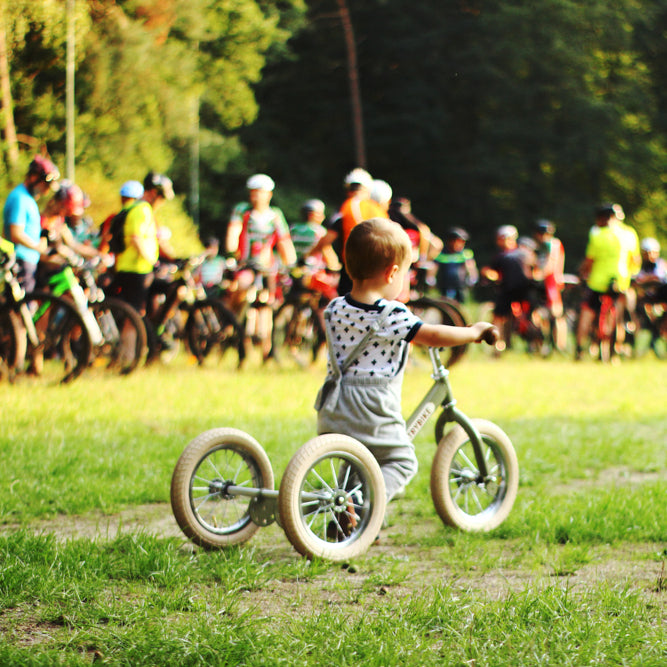 Child riding the Vintage Green Trybike balance bike outdoors