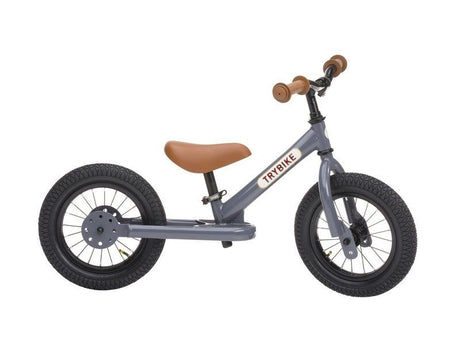 Child riding the Vintage Grey Trybike balance bike outdoors