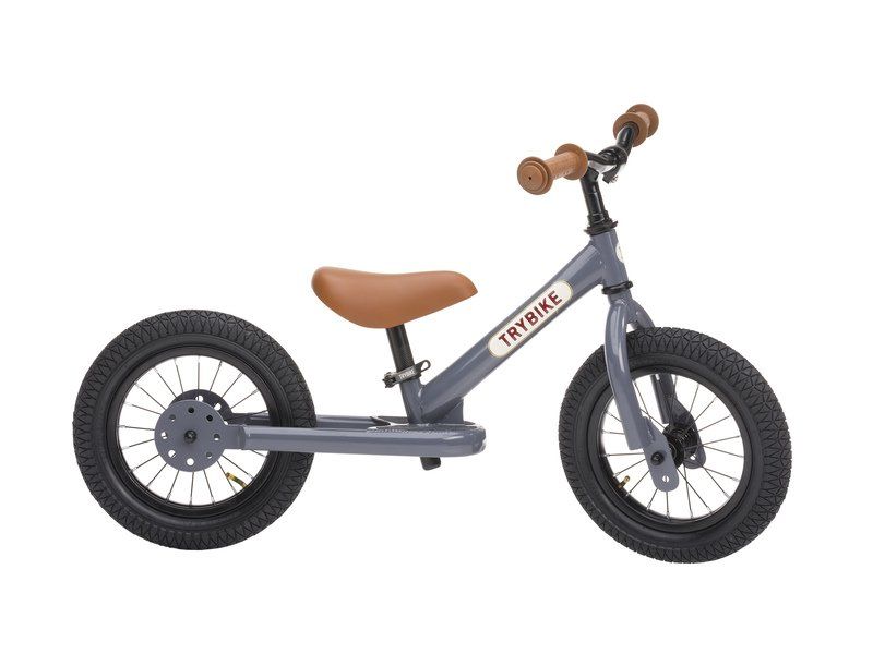 Child riding the Vintage Grey Trybike balance bike outdoors