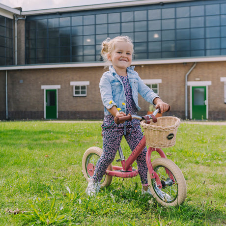 Child riding the Vintage Pink Trybike balance bike outdoors