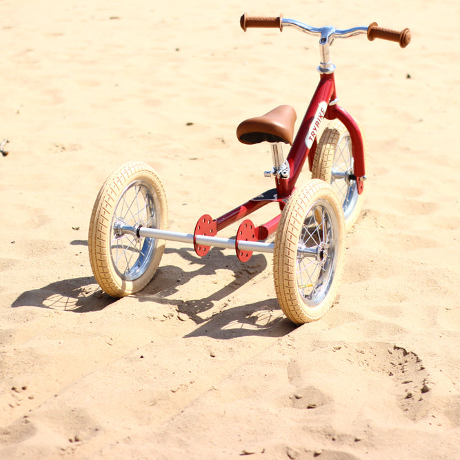 Child riding the Vintage Red Trybike balance bike outdoors