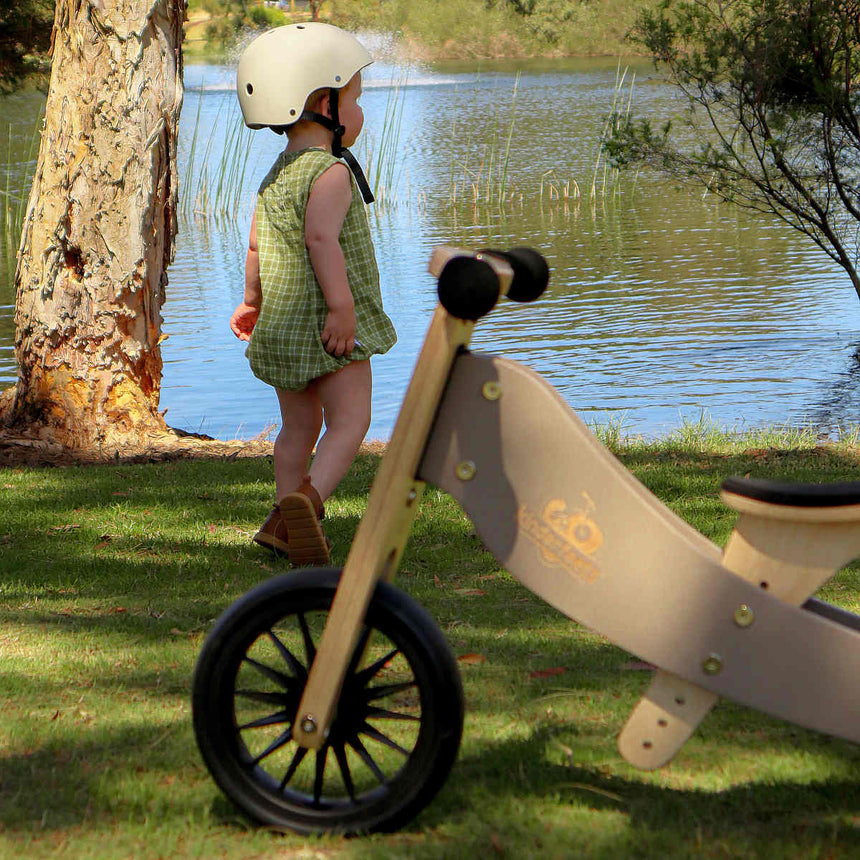 Kinderfeets Tiny Tot Plus Slate Grey wooden bike beside a lake